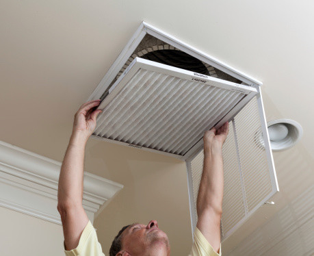 Technician replacing an air filter in a HVAC system