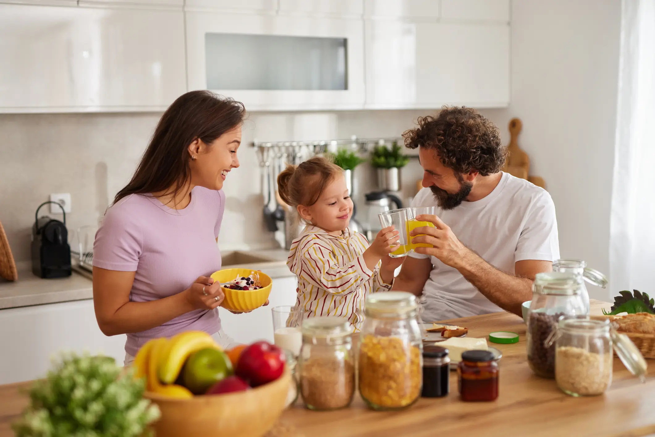 young family in bright kitchen eating healthy snacks